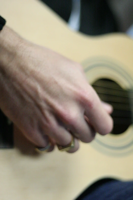 person's hand with ring holding a guitar strings