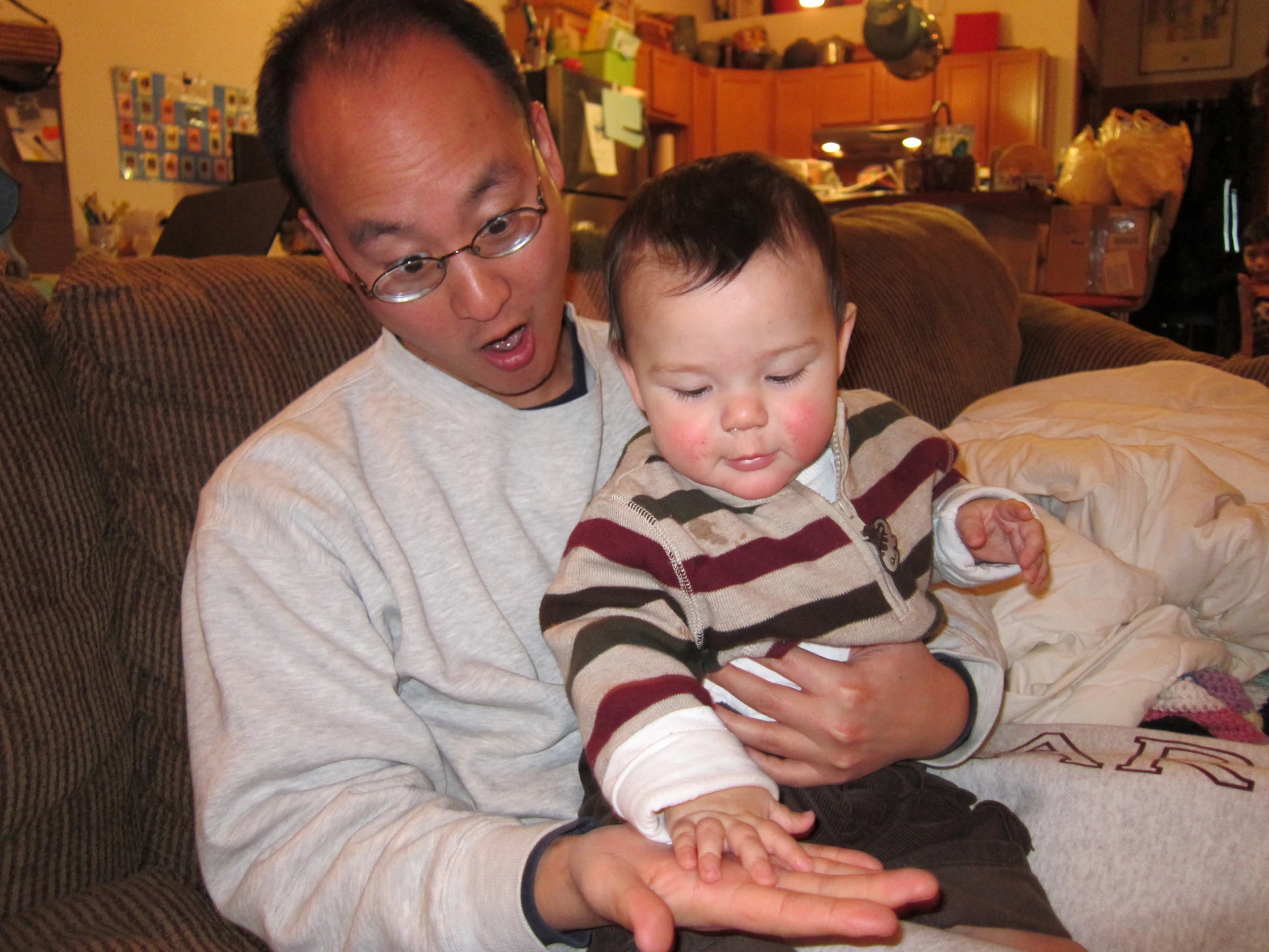 a man holding a baby who is wearing a  sweater