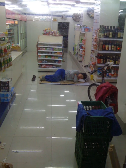 a man sleeping in the aisle of a market with several grocery crates