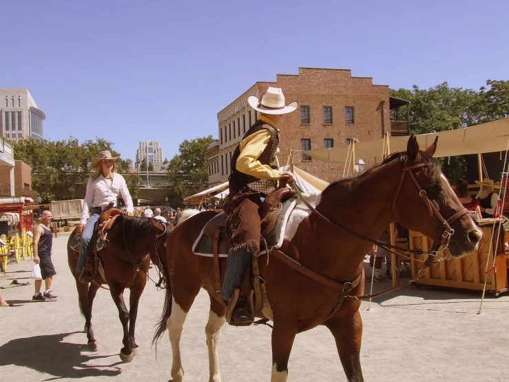 two people in cowboy hats are riding on horses