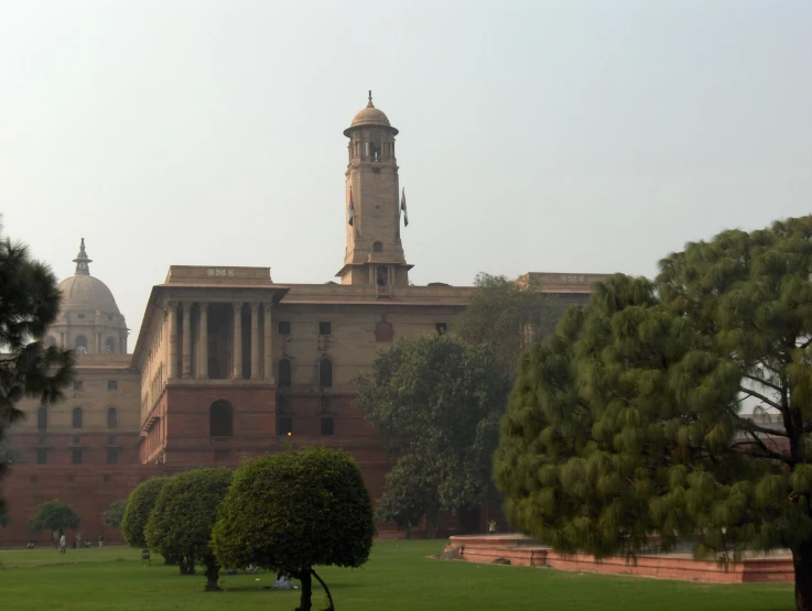 the large building with a tall clock tower is next to some trees