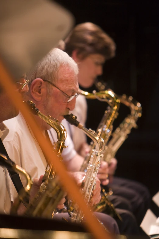 a couple of men sitting next to each other on saxophone