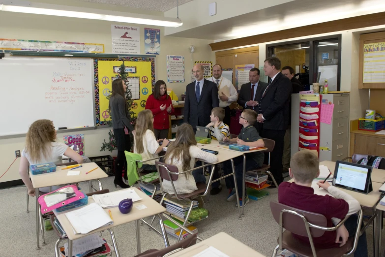 a group of children sitting at desks talking to adults