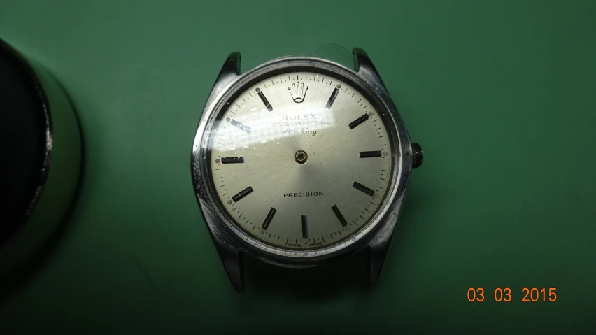 a silver analog watch sitting on top of green table