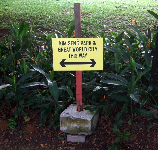the sign is sitting in front of plants with a yellow sign underneath it