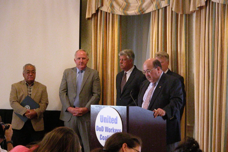 people in suits and ties standing at a podium