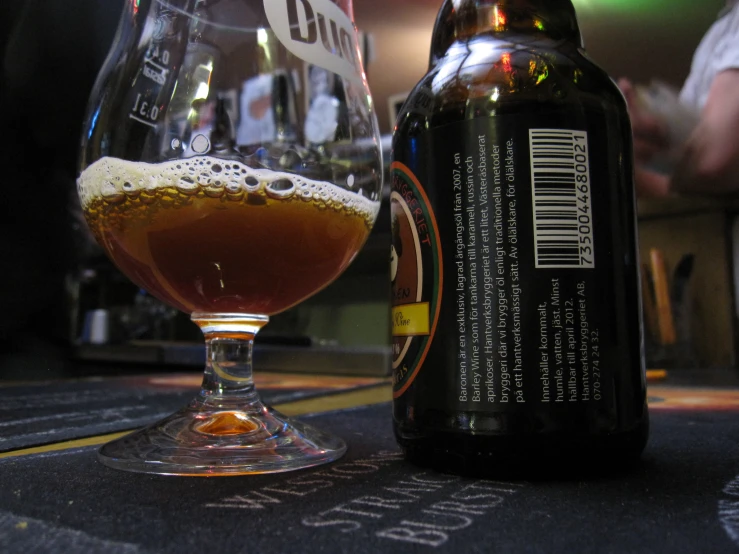 an empty glass sitting next to a bottle on a table