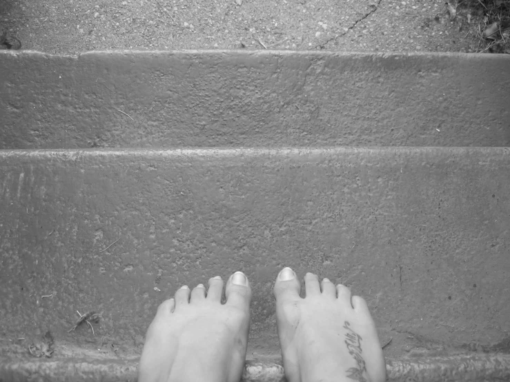 a person's feet on a stone walkway with a tattoo