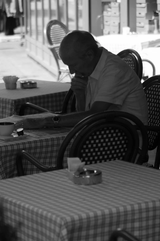 a man sits at a table looking down at his phone