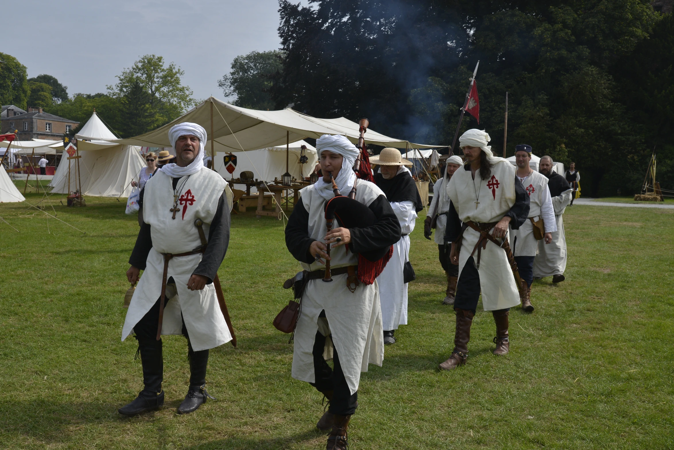 men in historical dress with sword, sword, and bonnet standing on grass