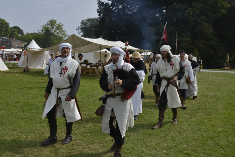 men in historical dress with sword, sword, and bonnet standing on grass