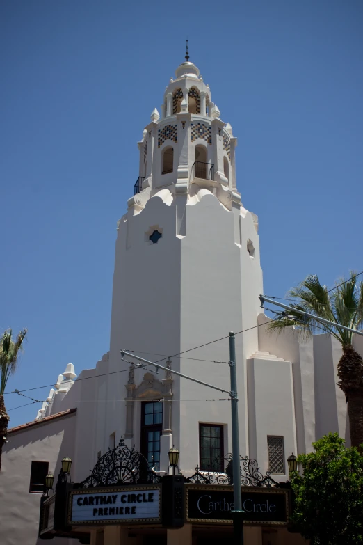 an ornate white building has a clock tower and palm trees