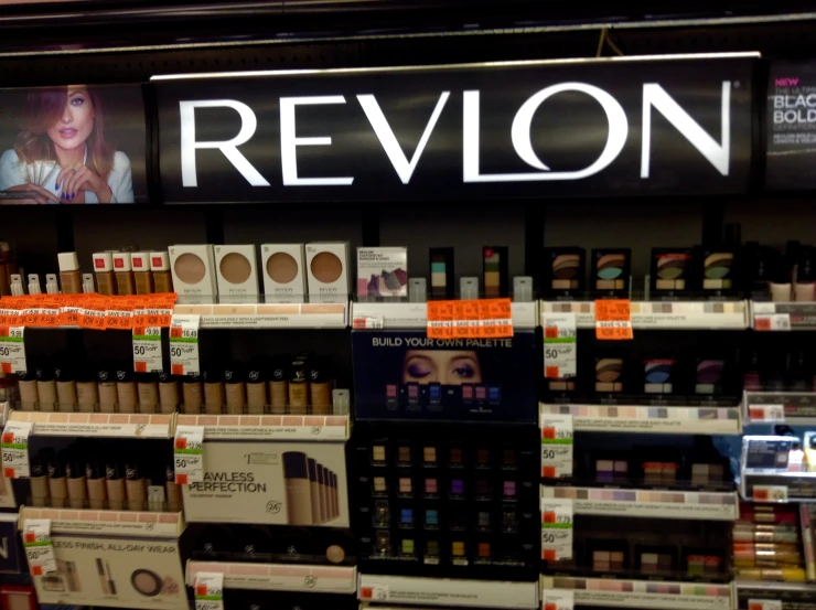 shelves displaying makeup in a store with the revlon sign