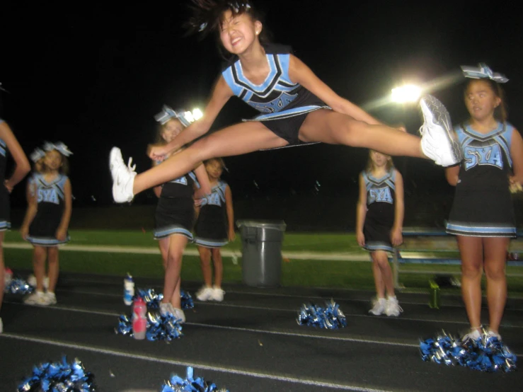 girl doing an aerial pose in the middle of a line of cheerleaders