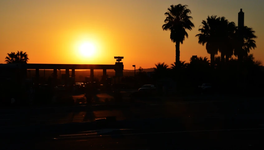 the sun is setting in the sky over cars