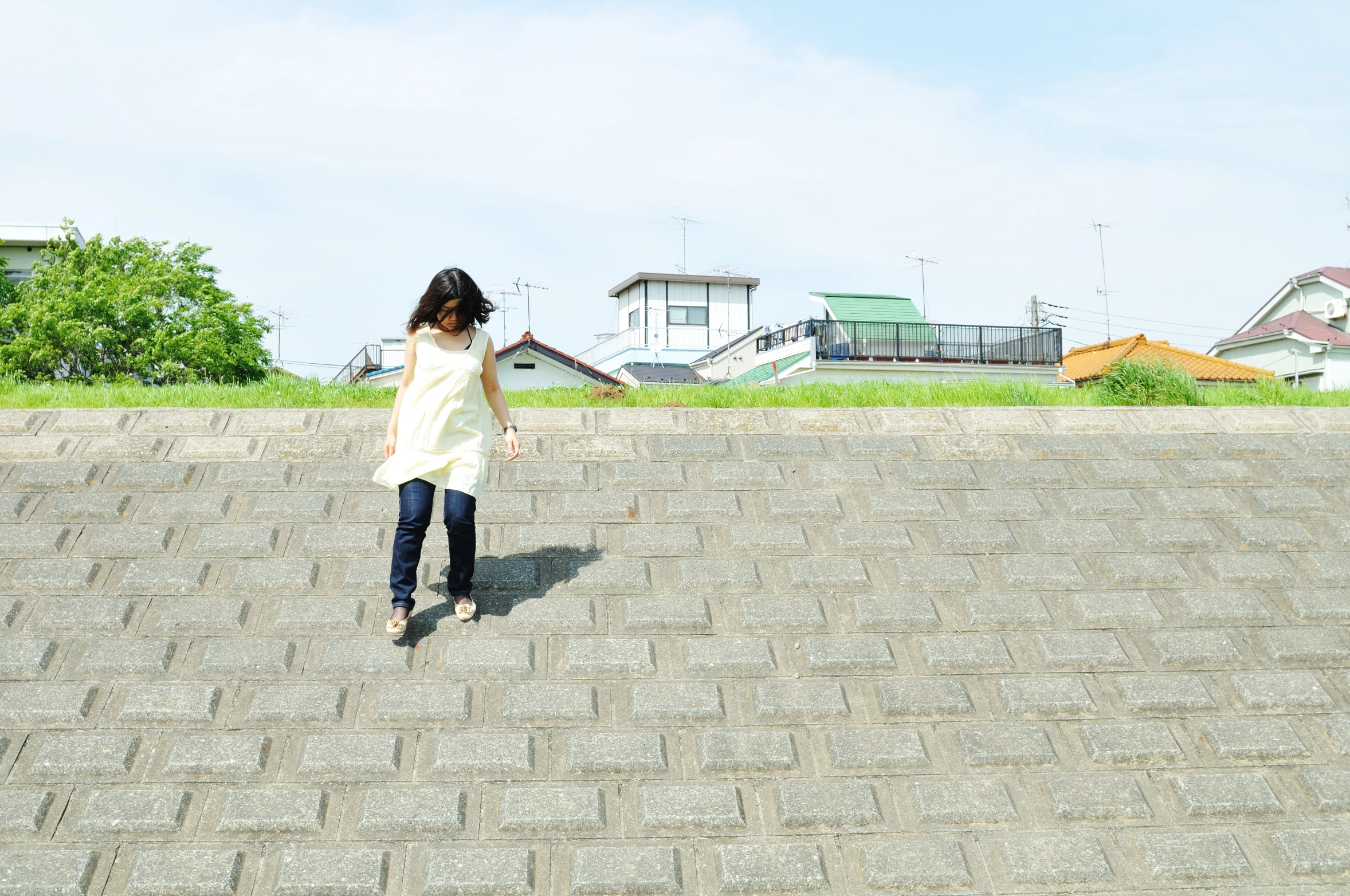 a woman in a white top is walking down a sidewalk