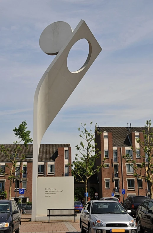 a tall, white sculpture sitting in a parking lot