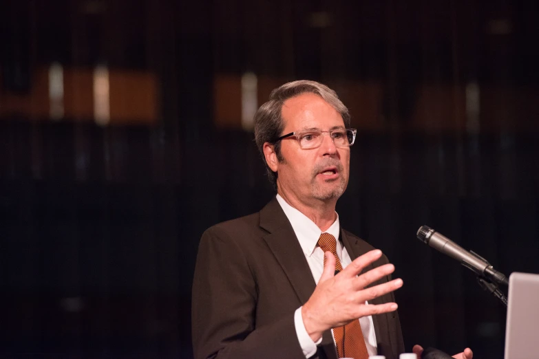 a man wearing a suit is giving a speech