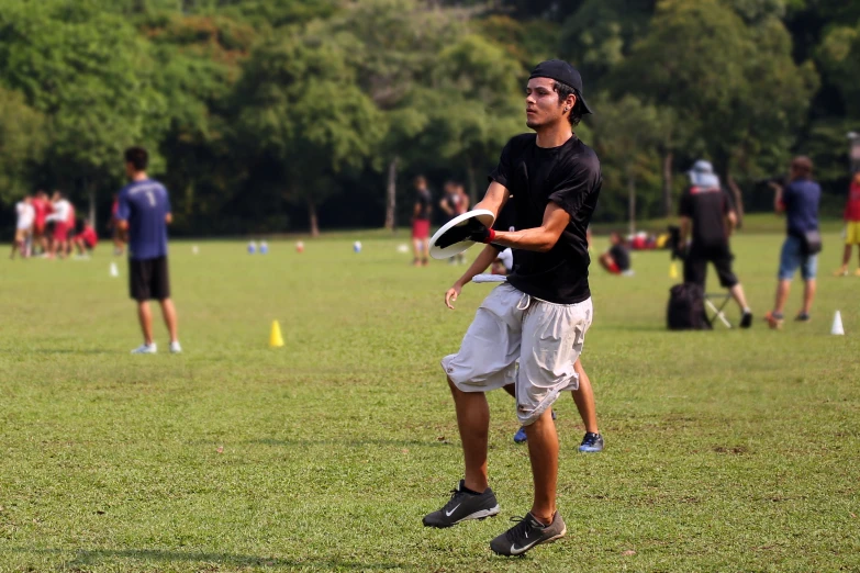 a man holding a frisbee while standing in the grass