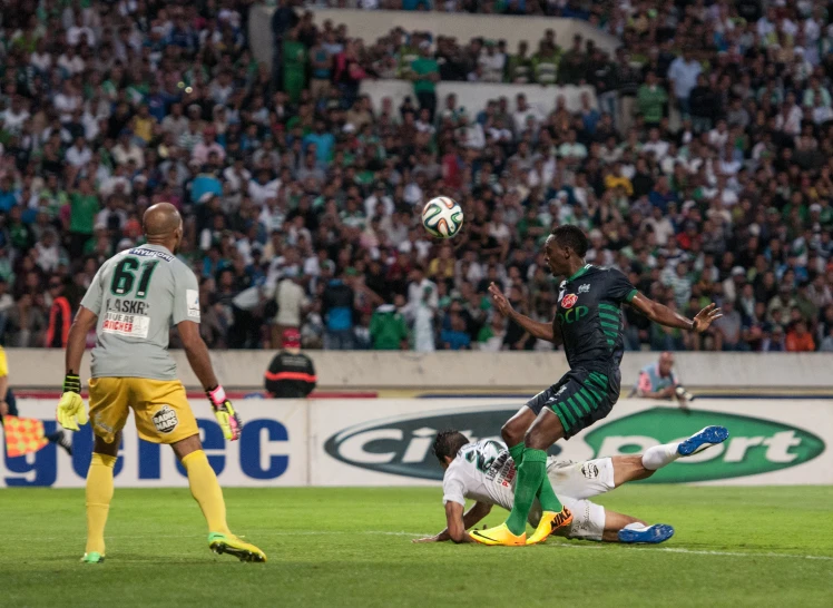 two soccer players are jumping high to try and kick the ball