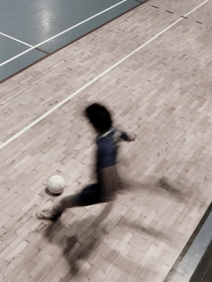 a man kicking a soccer ball while on the street
