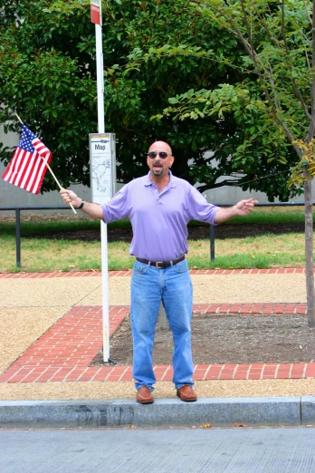 a man in a purple shirt holds an american flag