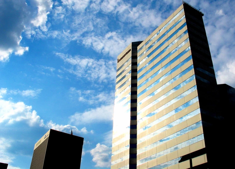 a large glass building in front of a bright blue sky