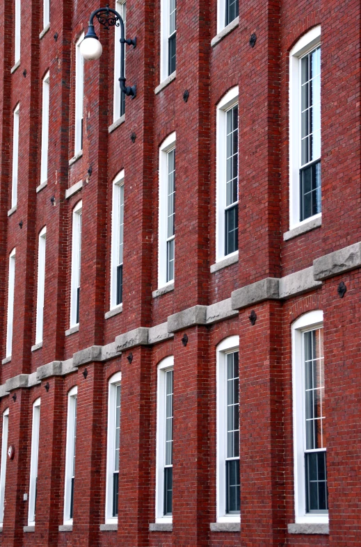 a tall brick building has a street light near the windows