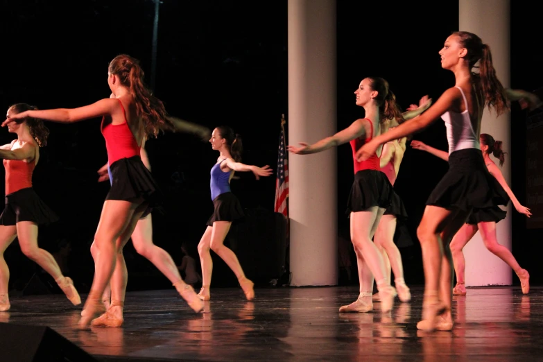 girls are performing on stage in dance with arms out