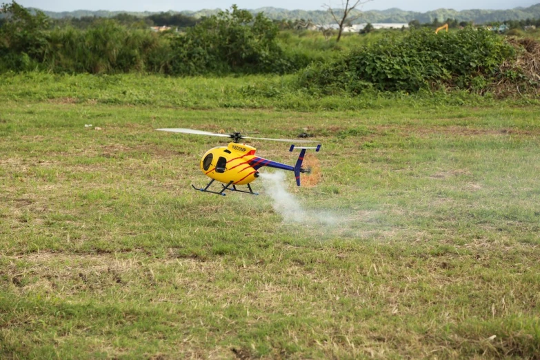 a yellow helicopter spraying water in the field