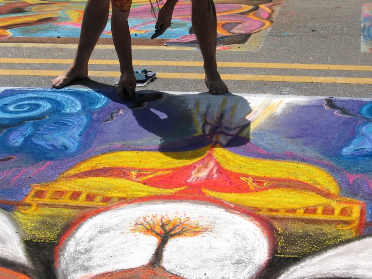 a person standing on a street with chalk art