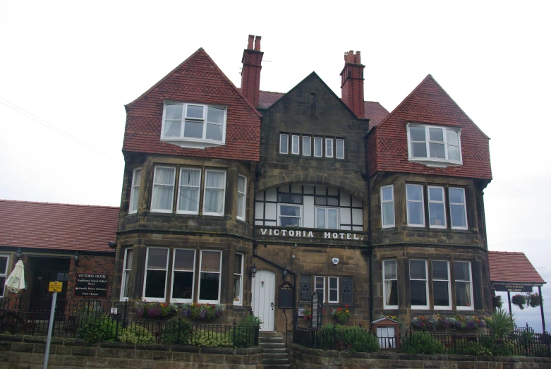 the two story brick house is next to a tall stone wall