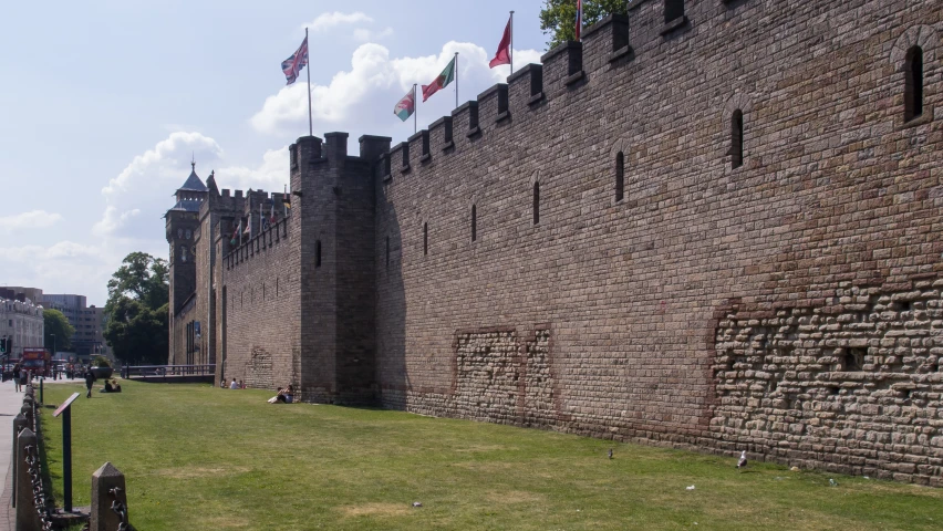 some flags in the air in front of a very large building