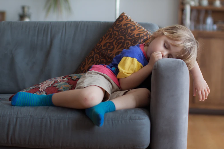 a girl is sitting on the couch asleep