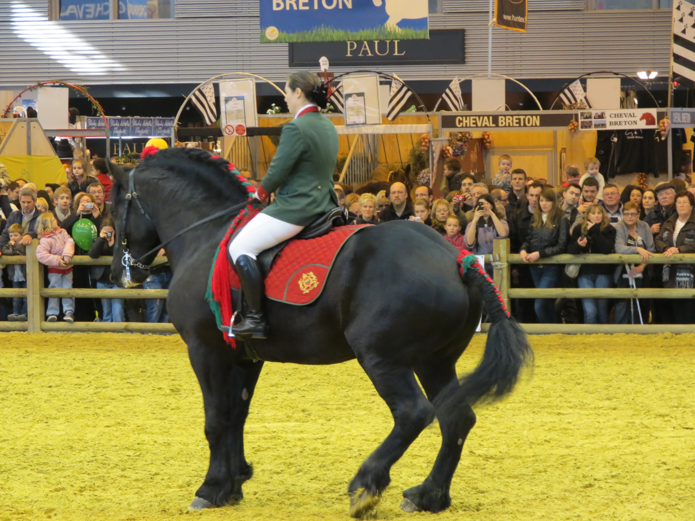 a woman in a uniform rides a horse with an audience behind