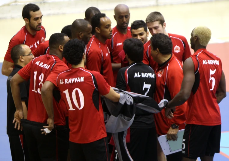 a bunch of men in red shirts talking to each other