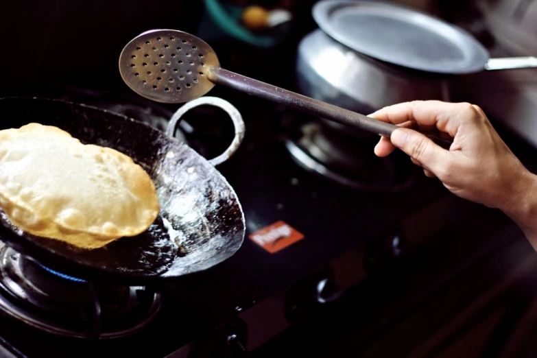 a hand holds a spatula over a set with food