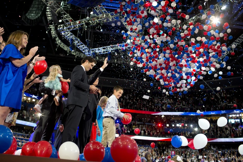 there are people standing on a stage with balloons