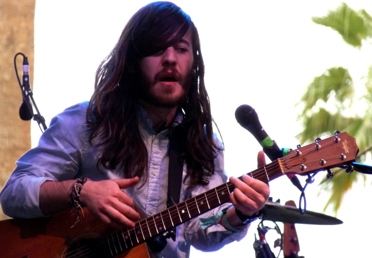 a man that is holding a guitar in his hand