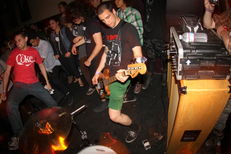 the man is playing a guitar in front of a group of people