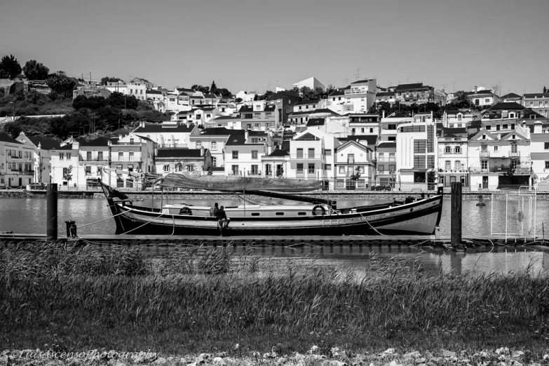 small long boat resting on a dock near a row of houses