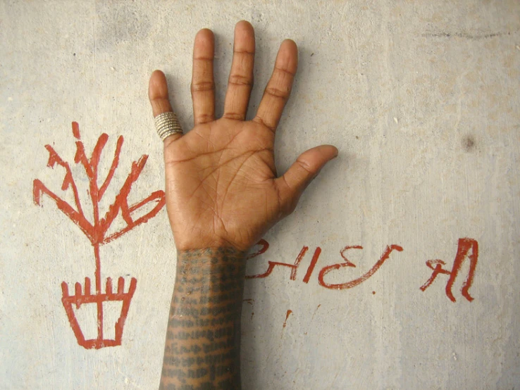 a person's hand over a wall with the graffiti that has been painted on it