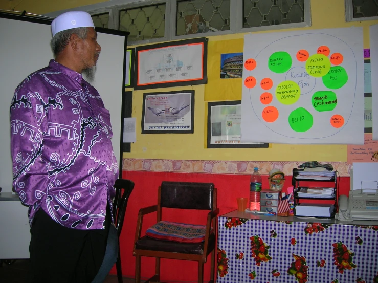 an older man is standing in front of a bulletin board