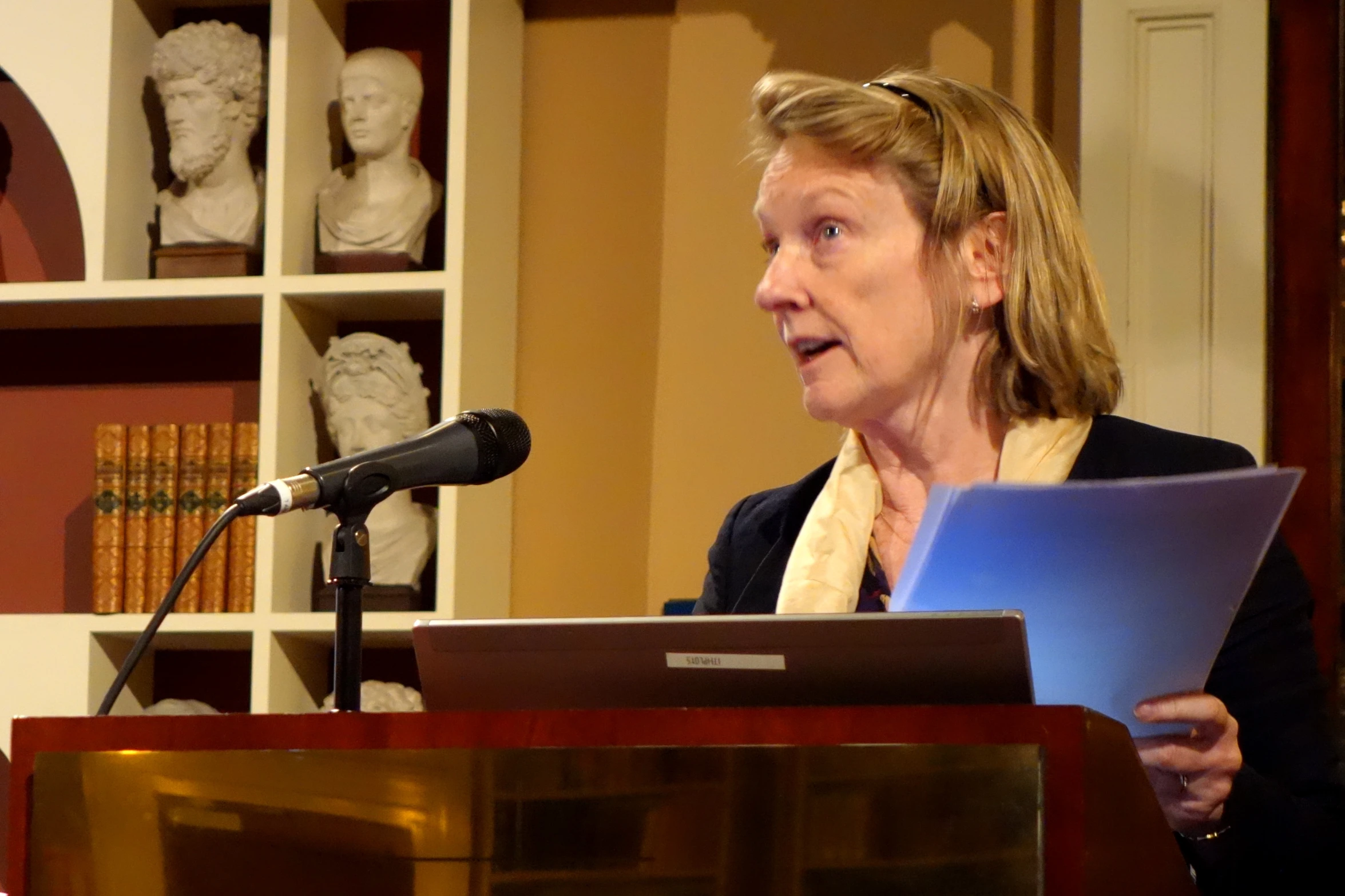 a woman is speaking from behind a lectern