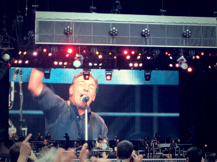 a concert that is showing a man singing and people waving