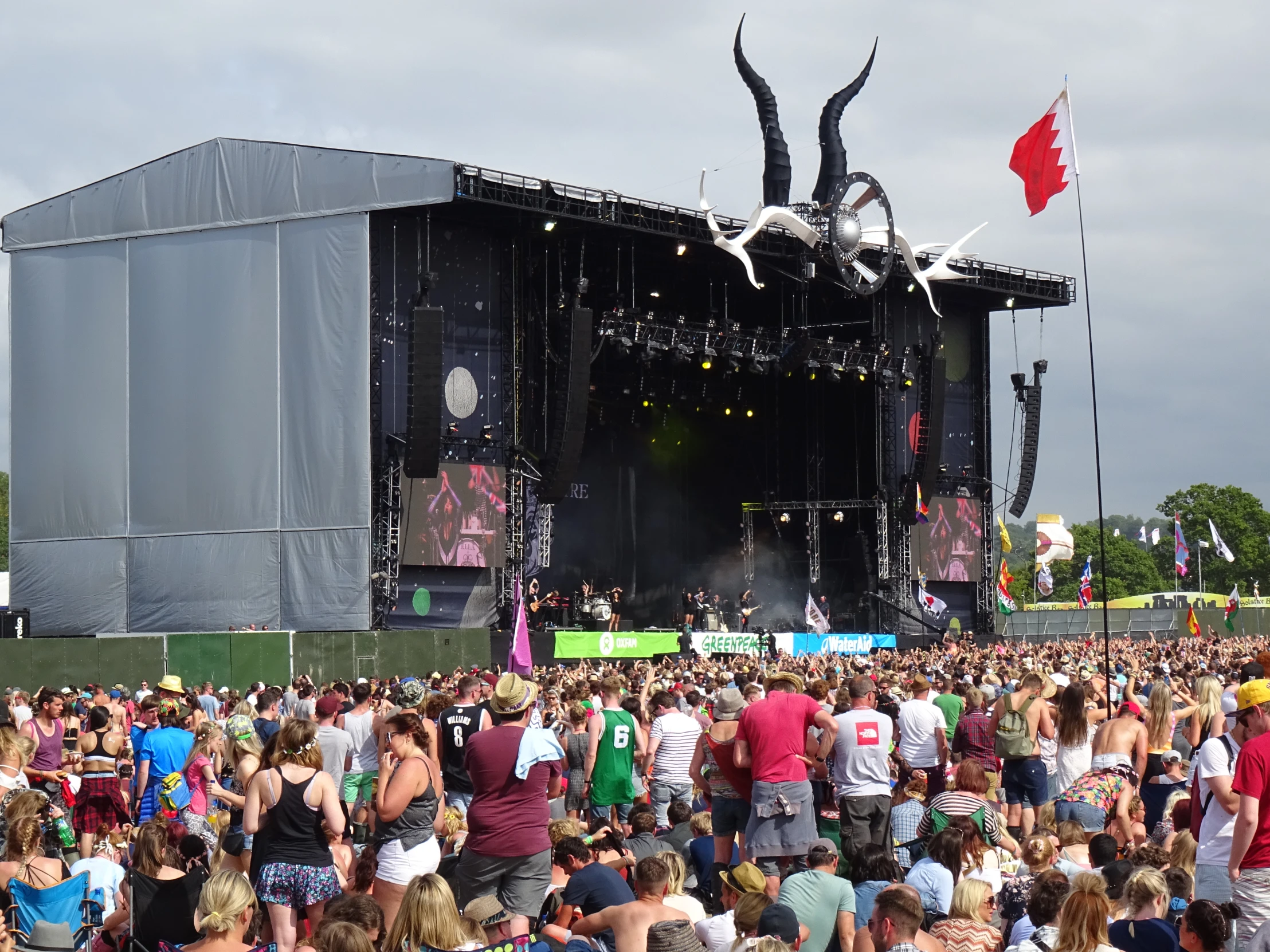 large crowd at an outdoor festival watching one man sing