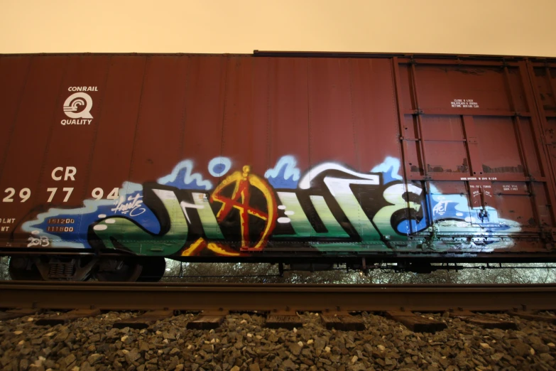 a train covered in graffiti driving down tracks