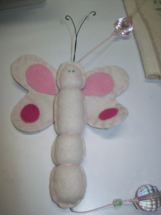 a pink and white moth shaped stuffed animal sitting next to a light