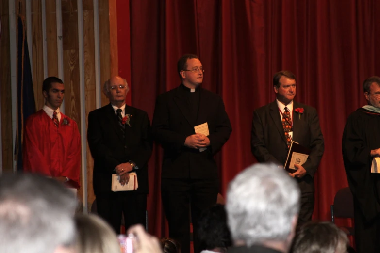 several men standing in front of a microphone while another man stands behind them