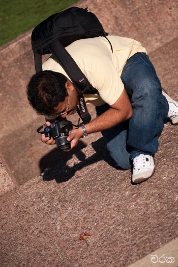 a man kneeling down holding a camera up to his face